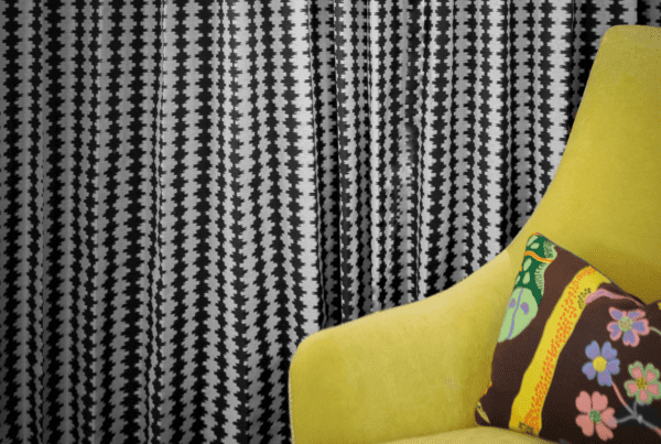 yellow lounge chair complementing the black and white print curtain